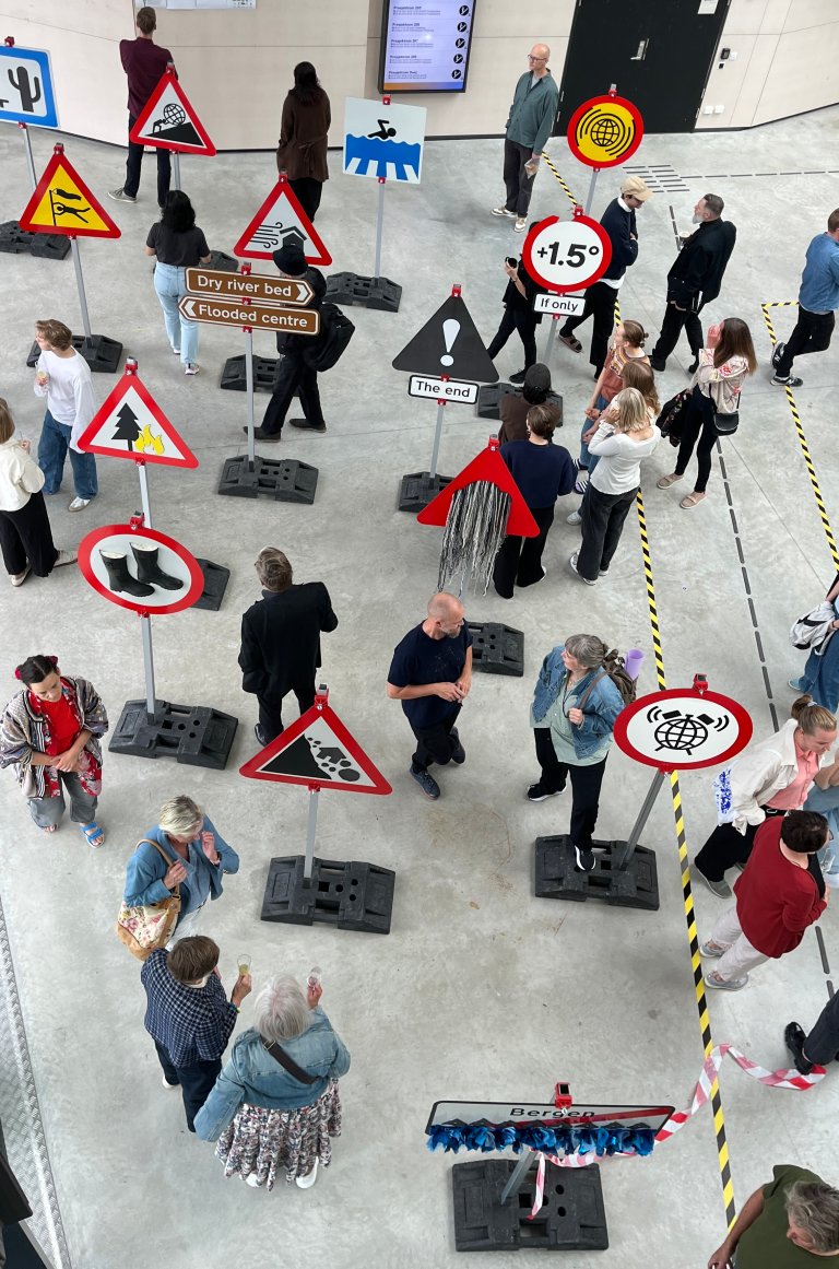 Folk står rundt i utstillingen under åpningen. Sett ovenfra