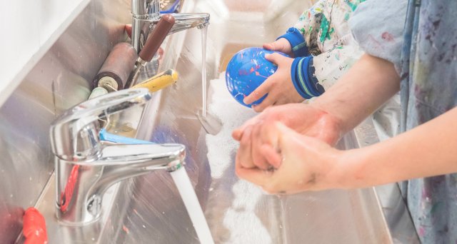 Barn vasker bort maling på hendene